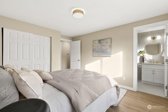 bedroom featuring ensuite bathroom, light hardwood / wood-style flooring, and a closet