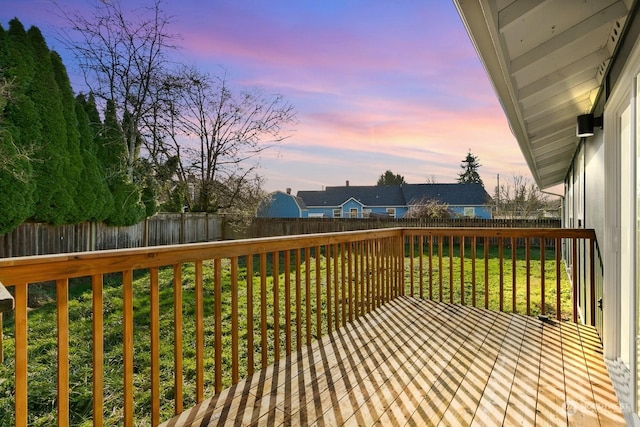 deck at dusk featuring a lawn