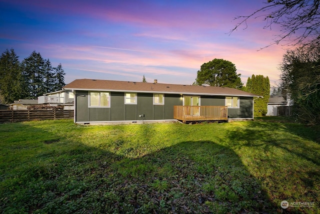 back house at dusk with a yard and a wooden deck