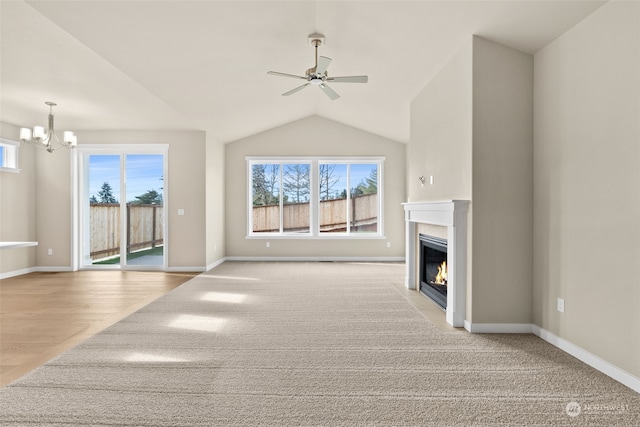 unfurnished living room featuring vaulted ceiling and ceiling fan with notable chandelier