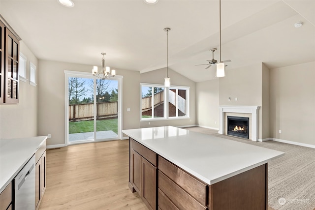 kitchen with ceiling fan with notable chandelier, decorative light fixtures, vaulted ceiling, stainless steel dishwasher, and light wood-type flooring