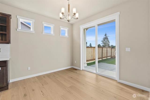 unfurnished dining area with an inviting chandelier and light hardwood / wood-style flooring