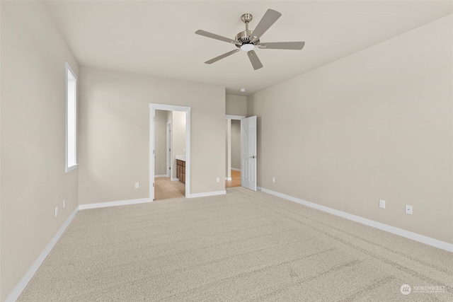 unfurnished bedroom featuring ceiling fan, light colored carpet, and ensuite bathroom