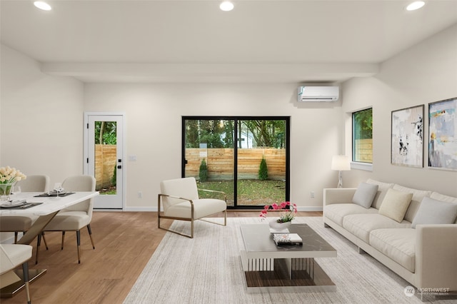 living room featuring beam ceiling, light hardwood / wood-style floors, and a wall unit AC