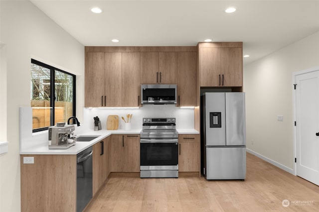 kitchen with stainless steel appliances, light hardwood / wood-style floors, and sink