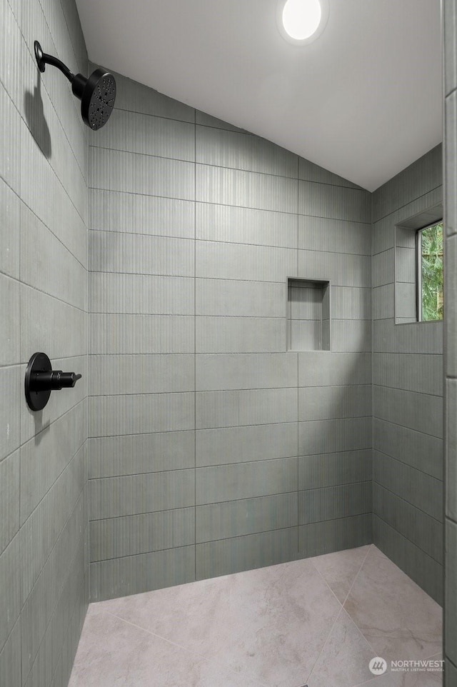 bathroom featuring tiled shower and lofted ceiling