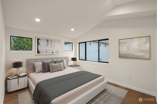 bedroom with multiple windows, hardwood / wood-style floors, and vaulted ceiling