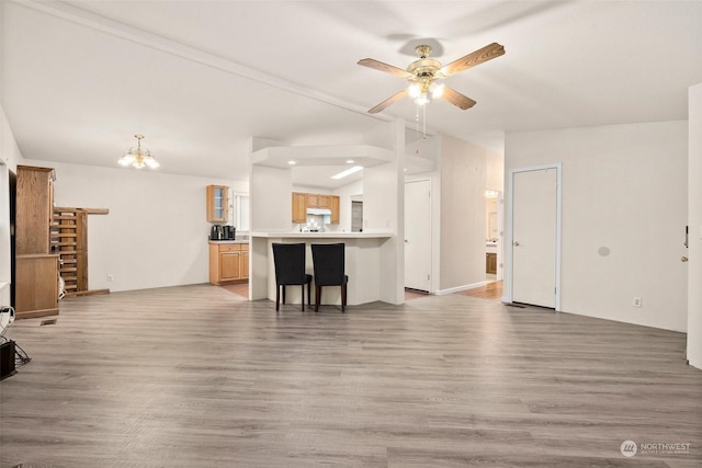 unfurnished living room with ceiling fan with notable chandelier and wood-type flooring