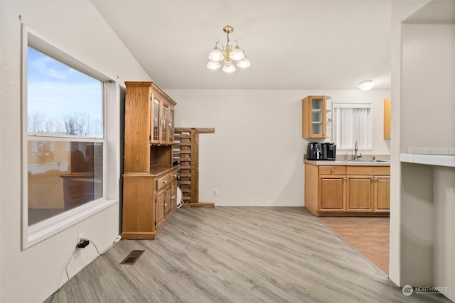 kitchen featuring a chandelier, light wood-type flooring, decorative light fixtures, and sink