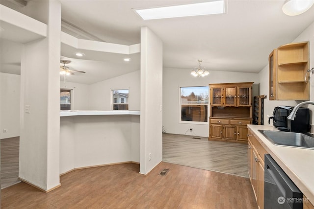 kitchen featuring dishwasher, sink, hanging light fixtures, and light hardwood / wood-style floors