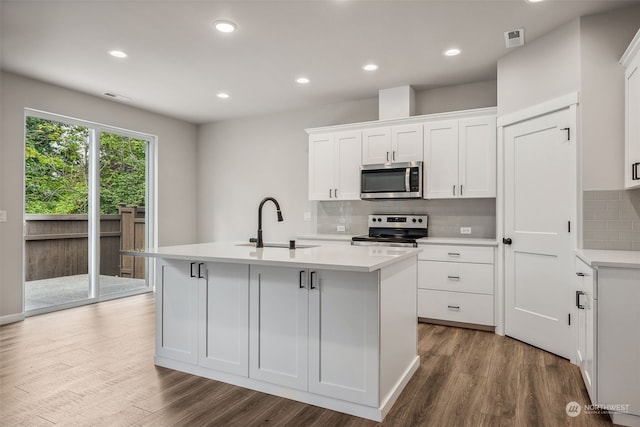 kitchen featuring a kitchen island with sink, white cabinets, sink, hardwood / wood-style flooring, and stainless steel appliances