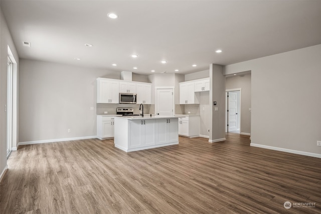 kitchen featuring light hardwood / wood-style flooring, white cabinetry, stainless steel appliances, and an island with sink