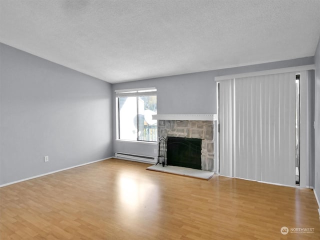 unfurnished living room with a stone fireplace, a baseboard radiator, a textured ceiling, and light wood-type flooring