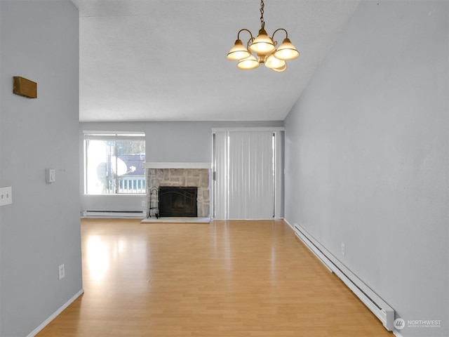 unfurnished living room featuring an inviting chandelier, a stone fireplace, light hardwood / wood-style flooring, and a baseboard radiator