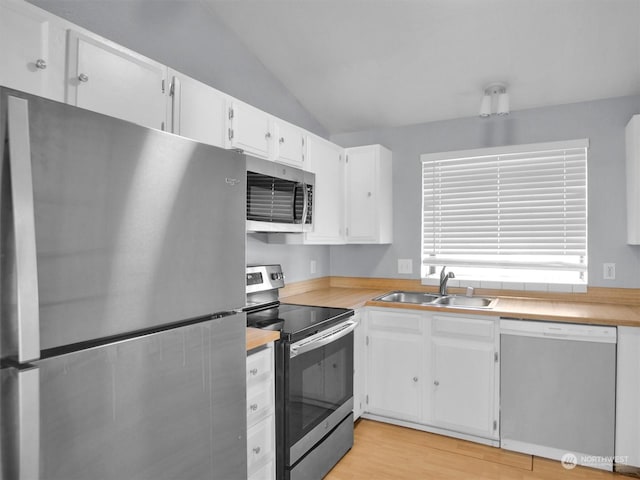 kitchen featuring white cabinetry, sink, stainless steel appliances, vaulted ceiling, and light wood-type flooring