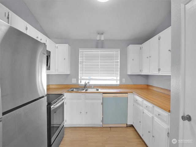 kitchen with white cabinets, appliances with stainless steel finishes, vaulted ceiling, and sink