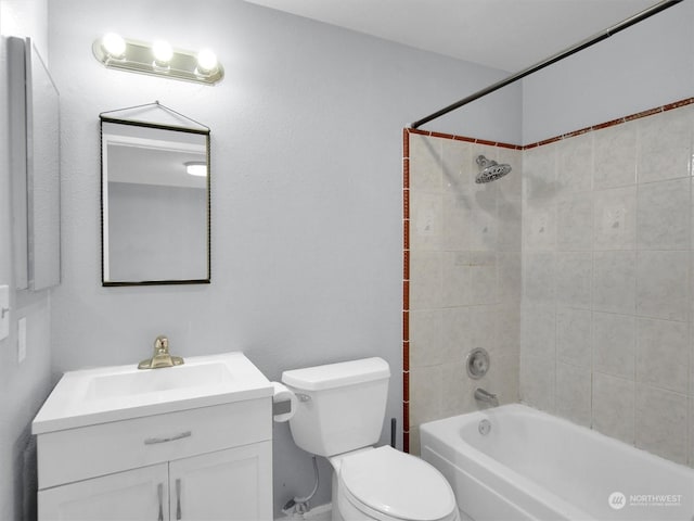 full bathroom featuring tiled shower / bath, vanity, and toilet