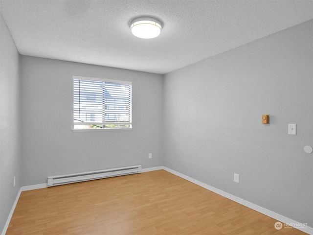 empty room featuring hardwood / wood-style flooring, a textured ceiling, and a baseboard radiator