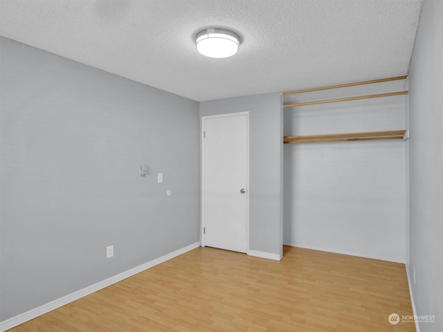 unfurnished bedroom with wood-type flooring, a textured ceiling, and a closet