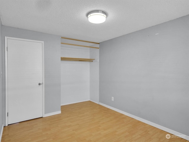 unfurnished bedroom with a closet, a textured ceiling, and hardwood / wood-style flooring