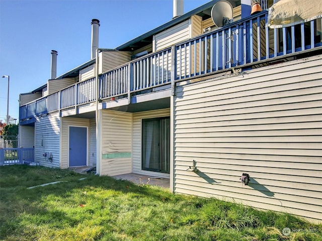 rear view of property with a lawn and a balcony