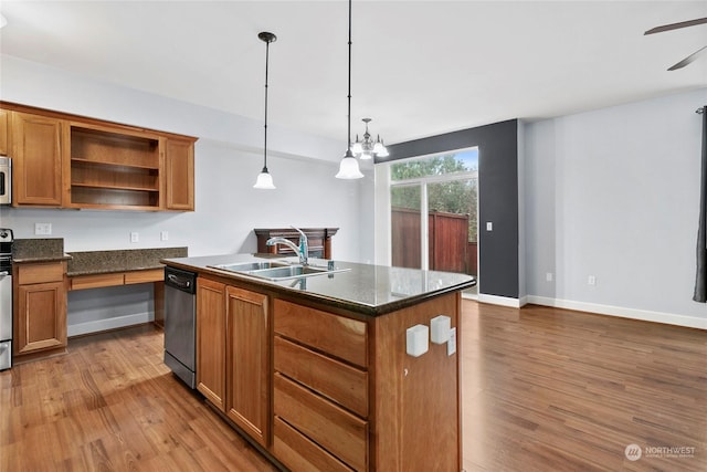 kitchen featuring a center island with sink, appliances with stainless steel finishes, wood finished floors, hanging light fixtures, and a sink