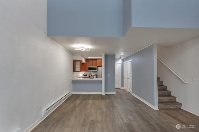 unfurnished living room with baseboard heating and dark hardwood / wood-style flooring