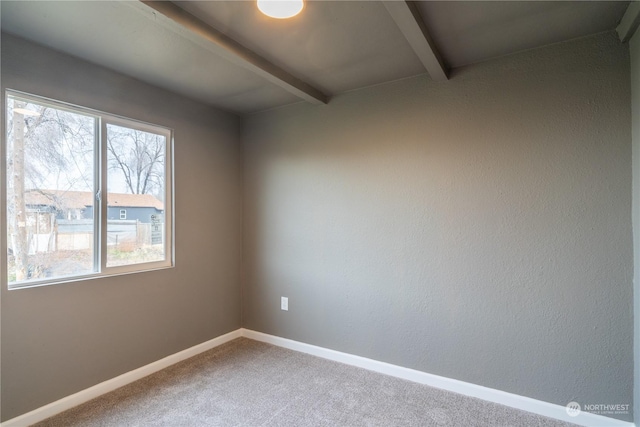 carpeted empty room with beamed ceiling