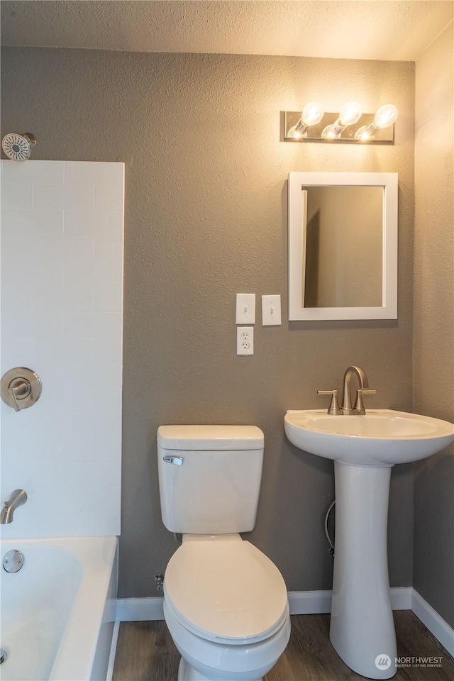 bathroom with hardwood / wood-style flooring, a bathtub, toilet, and sink