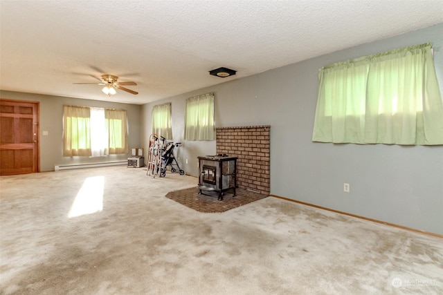 carpeted living room featuring a textured ceiling, a wood stove, ceiling fan, and a baseboard heating unit