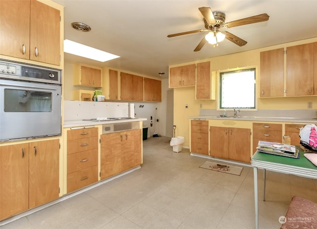 kitchen featuring white stovetop, oven, ceiling fan, and sink