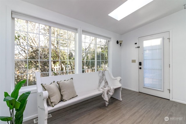 interior space with hardwood / wood-style floors and vaulted ceiling with skylight