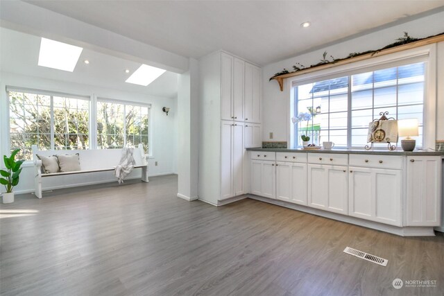 kitchen featuring a skylight, white cabinetry, and a wealth of natural light