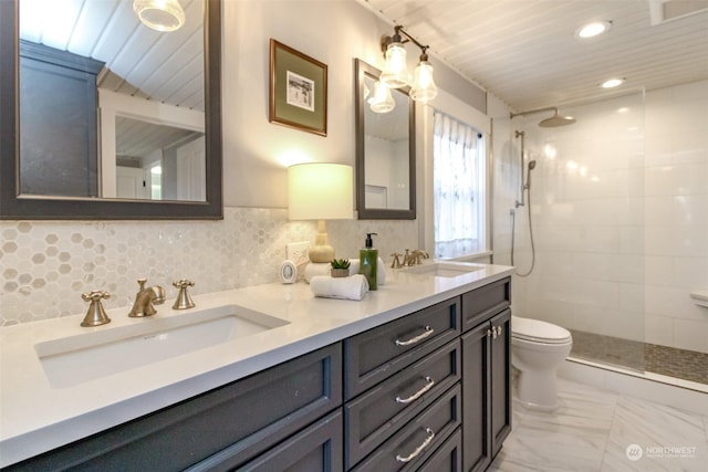 bathroom with vanity, toilet, a tile shower, and tasteful backsplash