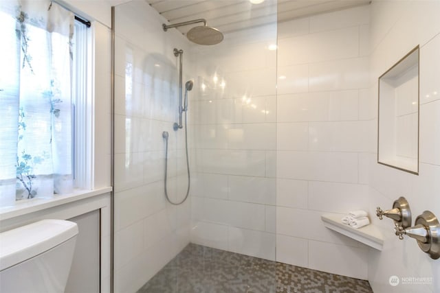 bathroom featuring a tile shower and toilet