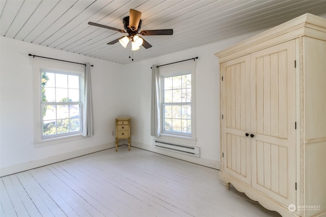 unfurnished room featuring ceiling fan, plenty of natural light, light hardwood / wood-style floors, and a baseboard heating unit