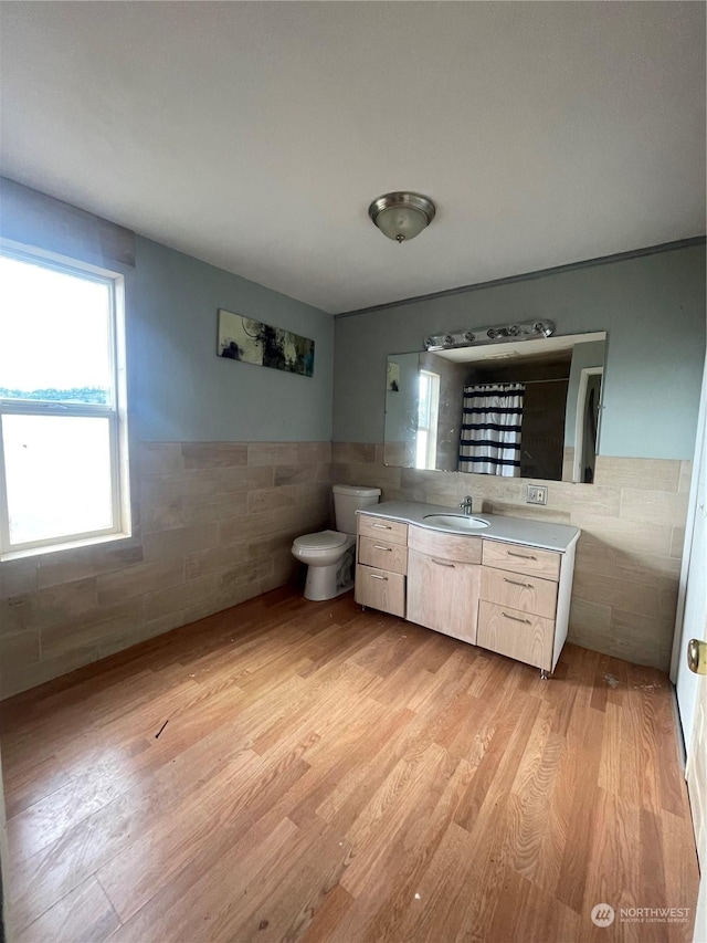 bathroom with tile walls, toilet, vanity, and wood-type flooring