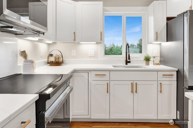 kitchen featuring sink, white cabinets, stainless steel appliances, and light hardwood / wood-style flooring