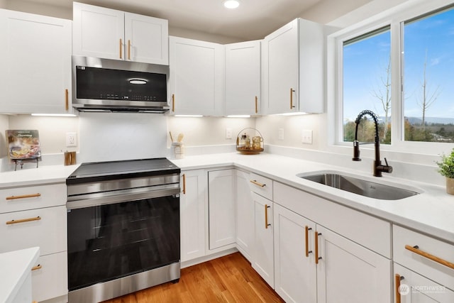 kitchen with white cabinetry, sink, light hardwood / wood-style flooring, and appliances with stainless steel finishes