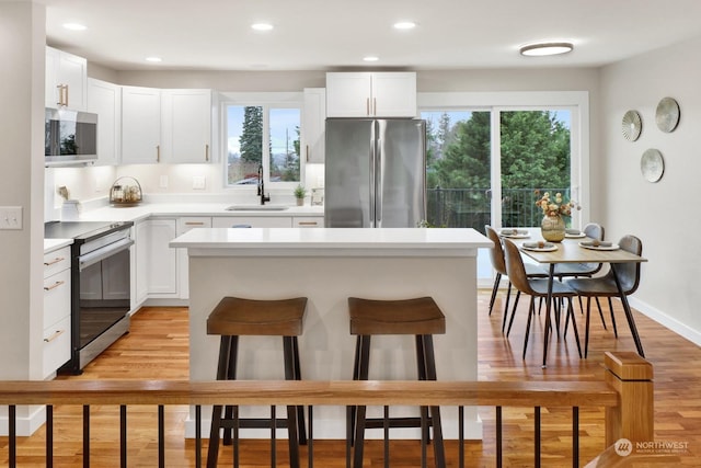 kitchen featuring stainless steel appliances, white cabinetry, and a healthy amount of sunlight