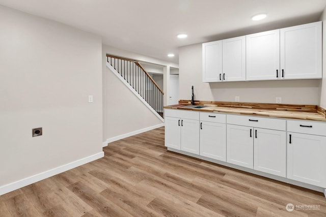 kitchen featuring white cabinets, wood counters, light hardwood / wood-style floors, and sink