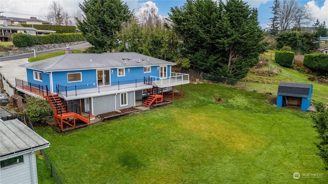 rear view of property featuring a lawn, a shed, and a wooden deck