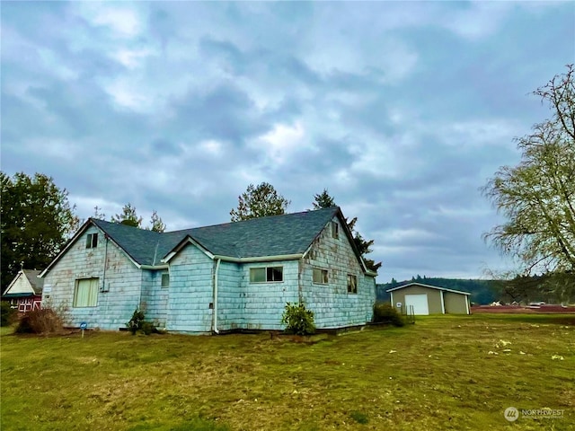 back of house featuring a lawn, a garage, and an outbuilding