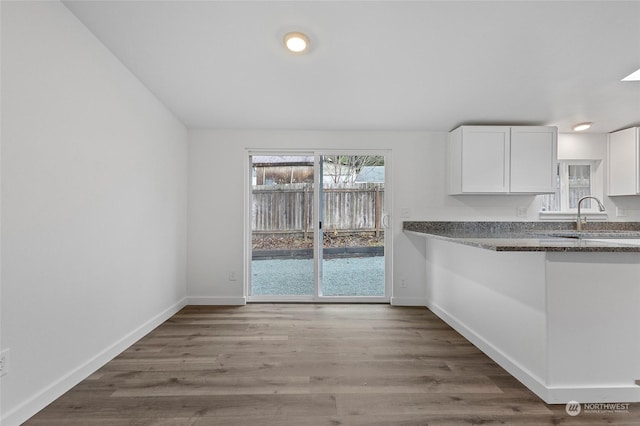 kitchen with hardwood / wood-style floors, white cabinetry, and sink