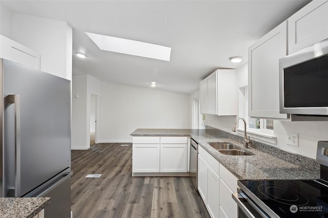 kitchen featuring a skylight, white cabinetry, sink, stainless steel appliances, and dark hardwood / wood-style flooring