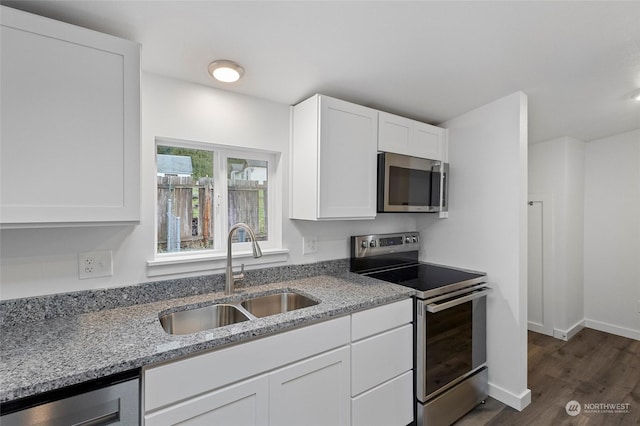 kitchen featuring light stone counters, stainless steel appliances, dark wood-type flooring, sink, and white cabinets