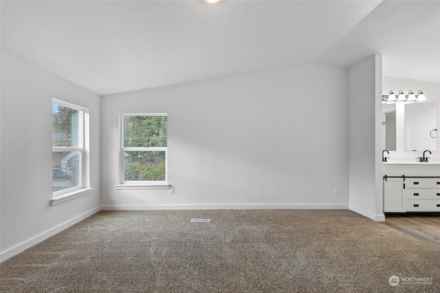 unfurnished bedroom featuring sink, carpet, and lofted ceiling