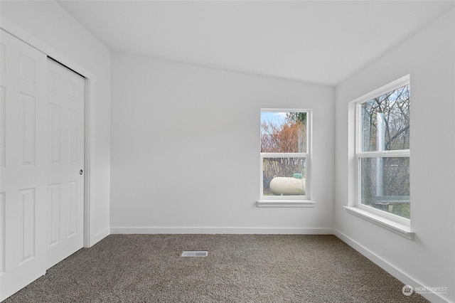 unfurnished bedroom with dark carpet, lofted ceiling, and a closet