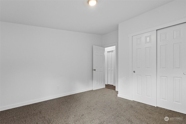 unfurnished bedroom featuring a closet and dark carpet