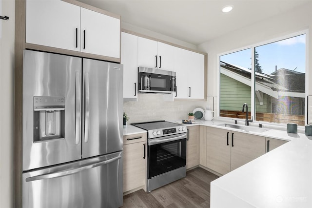 kitchen featuring backsplash, dark hardwood / wood-style flooring, stainless steel appliances, sink, and white cabinetry